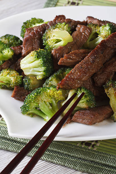 istock pieces of beef with broccoli close-up and chopsticks. Vertical 476093860