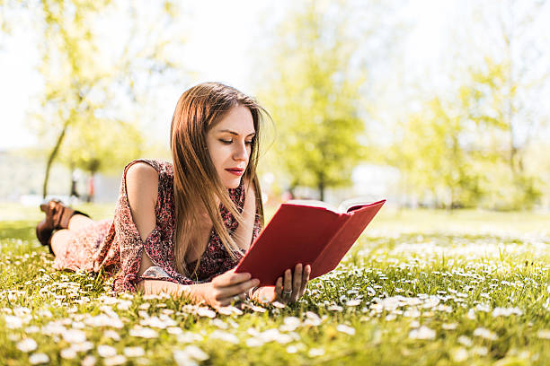 istock Young woman relaxing in grass and reading a book. 476098672