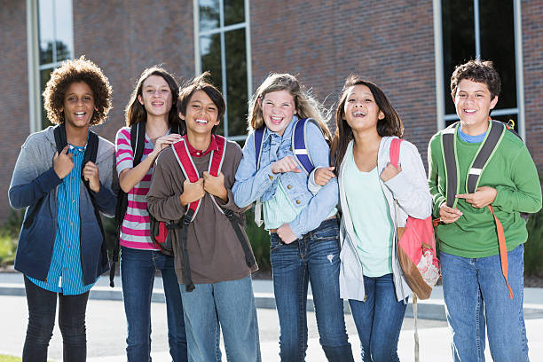 Students standing outside building Multi-ethnic group of students standing outside school building. teenager back to school group of people student stock pictures, royalty-free photos & images