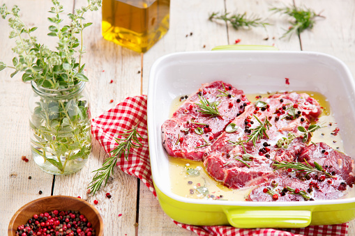 Raw beef steaks with olive oil, herb and pepper. Marinated meat.