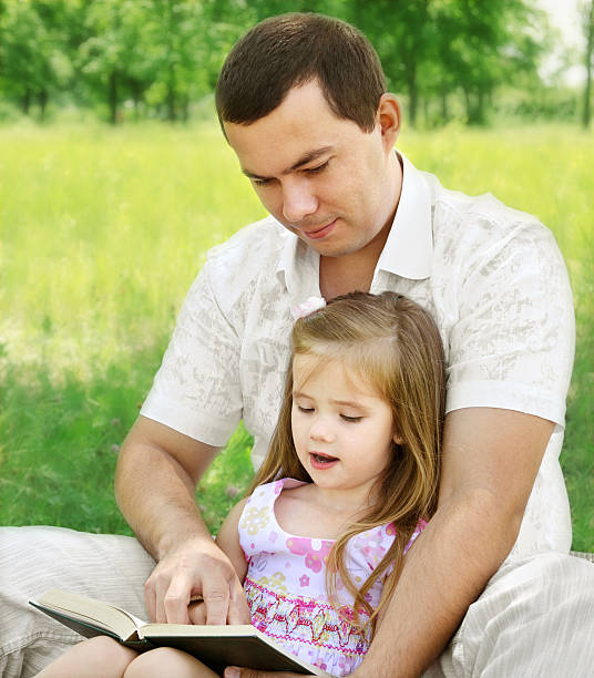 istock Father with daughter reading in the park 476110021
