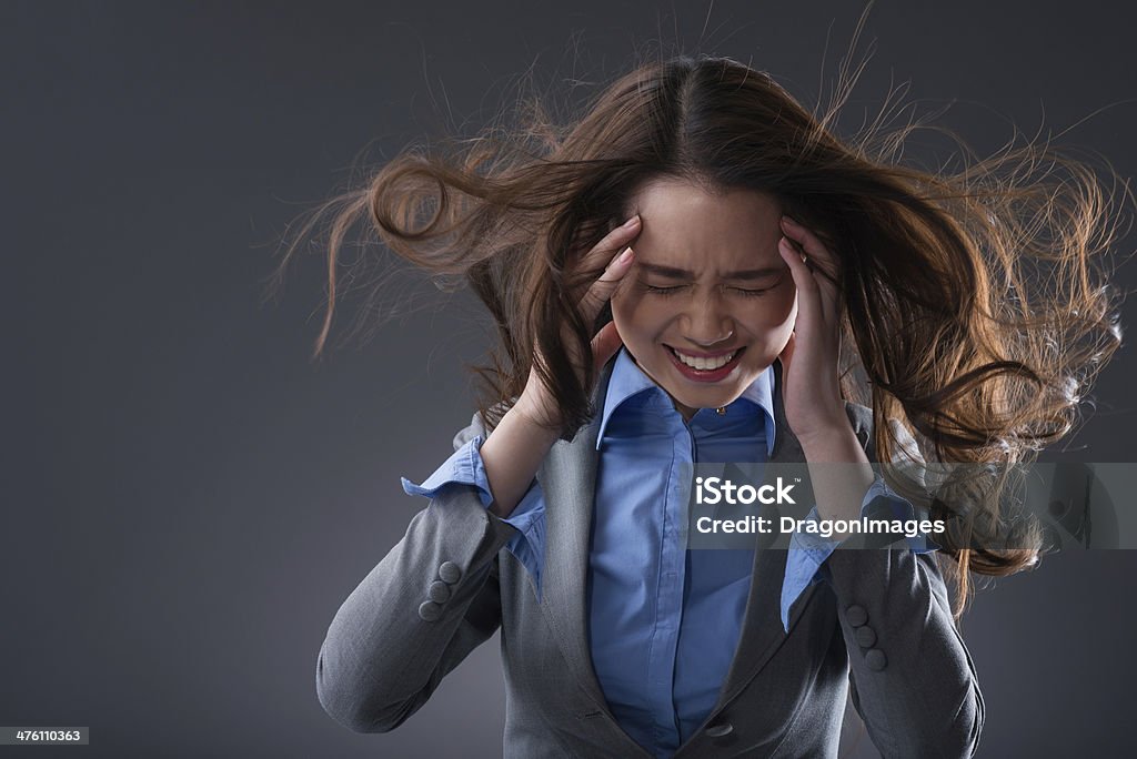 I dont want to hear you! Stressed business woman holding her head on a grey background Adult Stock Photo