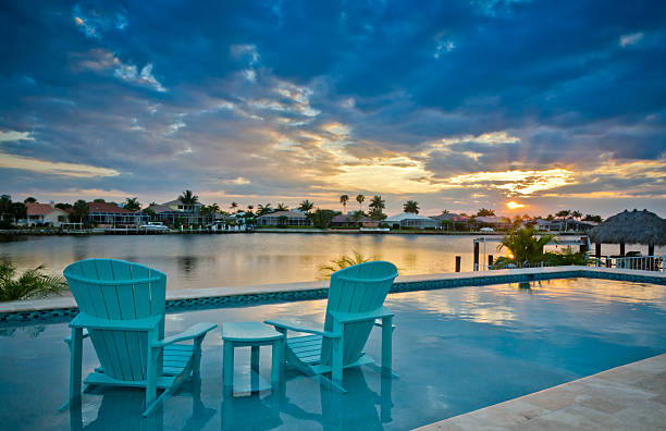 Sunset by the Pool Florida sunset on the bay overlooking a pair of chairs by a swimming pool. marco island stock pictures, royalty-free photos & images