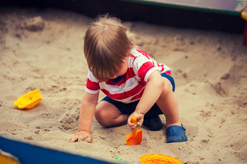 A boy enjoys digging a deep hole at a beach.