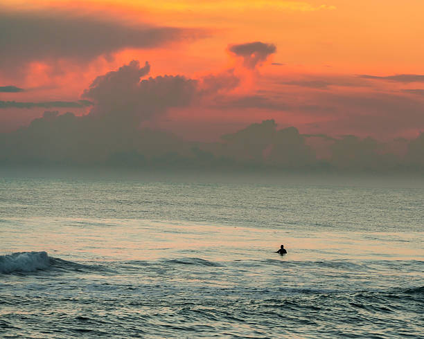 Surfer in water at sunrise