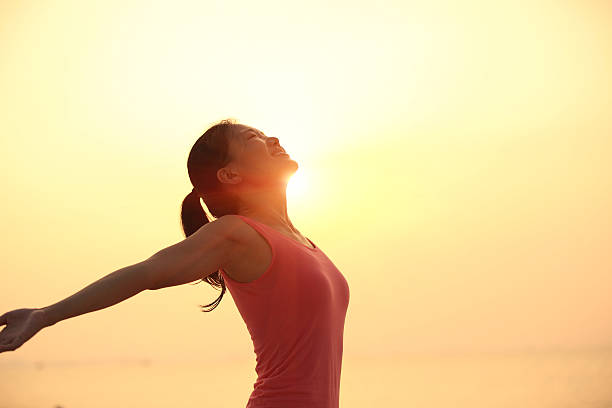 istock cheering  woman open arms under  sunrise on beach 476117475