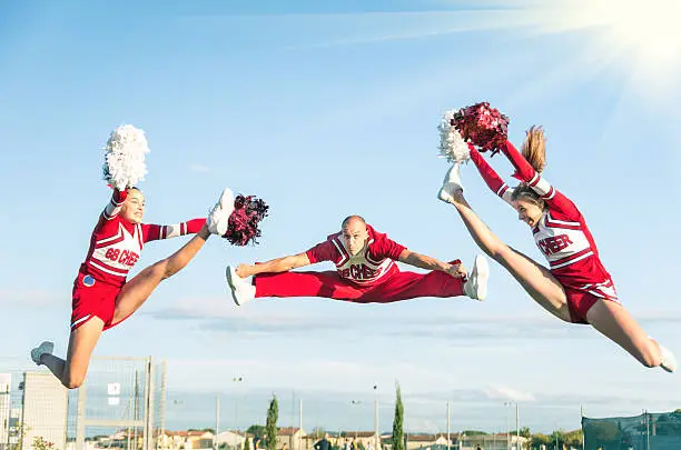 Cheerleaders team performing a Jump with male Coach