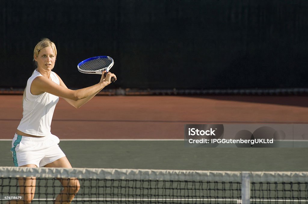 Young female tennis player swinging racket at court One Woman Only Stock Photo