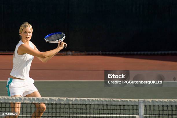 Young Female Tennis Player Swinging Racket At Court Stock Photo - Download Image Now