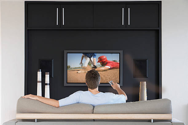 homme regardant la télévision sur de baseball - baseball cap photos et images de collection