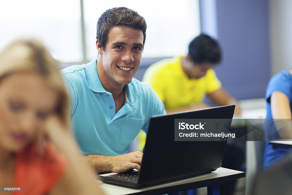 college boy using laptop in lecture hall handsome college boy using laptop in lecture hall Adult Stock Photo