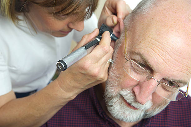 Nurse inspects patient's ear with an auroscope Nurse inspects patient's ear with an auroscope - the ear drum is evident from the image - all clear! Earlobe stock pictures, royalty-free photos & images