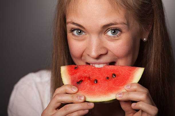istock Attractive Girl Biting a Watermelon Against Gray 476125688
