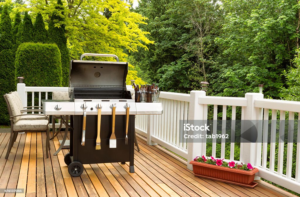 BBQ cooker and cookware ready to cook Photo of a clean barbecue cooker with cookware and cold beer in bucket on cedar wood patio. Table and colorful trees in background. Barbecue Grill Stock Photo