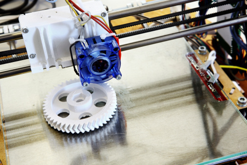 3D printer creating a white plastic gear