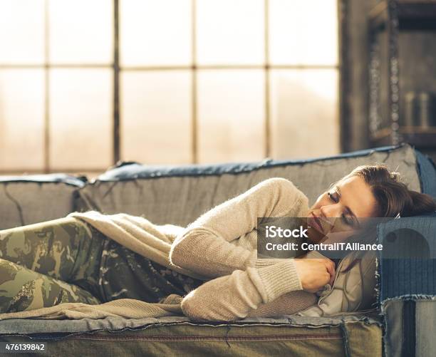 Woman Napping On Sofa In A City Loft Stock Photo - Download Image Now - 2015, Adult, Brown Hair