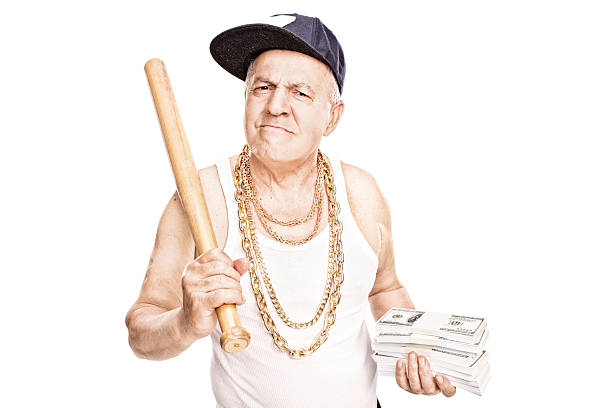 Mature gangster holding a bat and money Mature gangster with gold chains holding a baseball bat and stacks of money isolated on white background men baseball baseball cap baseball bat stock pictures, royalty-free photos & images