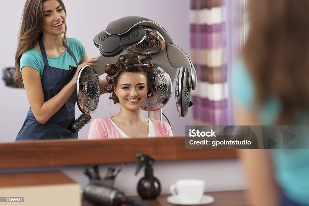 Belle femme assis à la clientèle sous un sèche-cheveux et des rouleaux - Photo de Adulte libre de droits