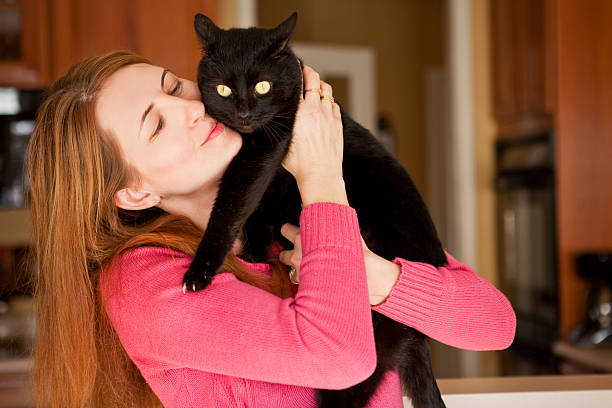 A 41 year old woman hugging her black cat.
