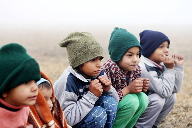 Three Poor Children Sitting in Winter Season Outdoor Portrait.