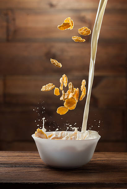 istock Falling corn flakes with milk splash on wood 476157744