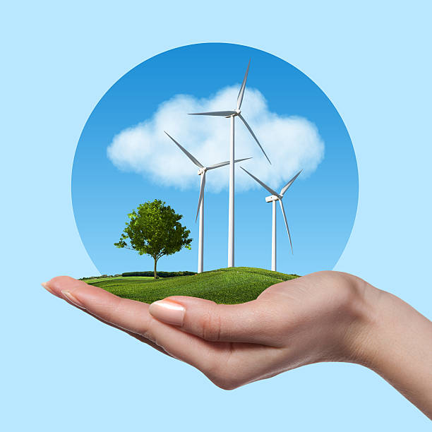 istock Wind turbines with tree in female hand against blue sky 476160740