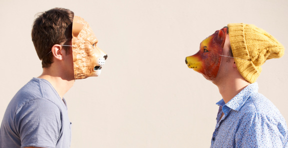Two young hipsters facing off while wearing animal masks
