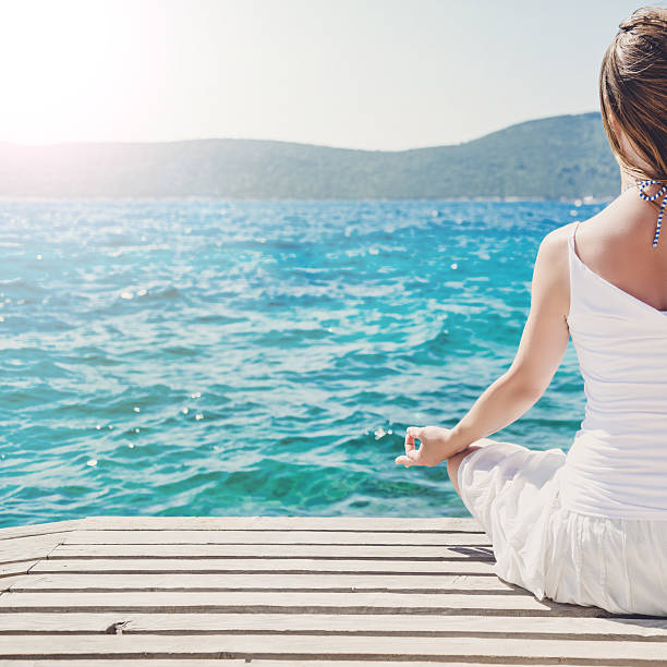 istock Woman meditating at the sea 476164192