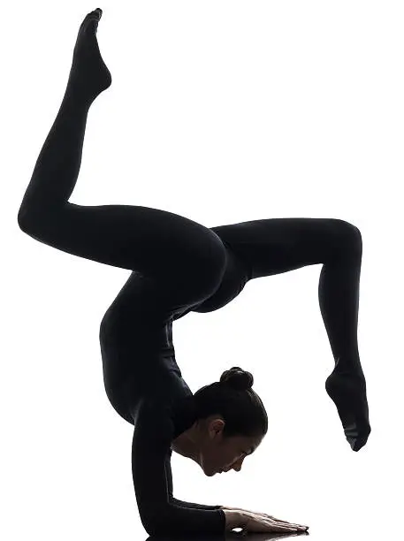 one caucasian woman contorsionist practicing gymnastic yoga  in silhouette   on white background