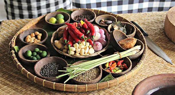 A platter filled with ingredients for a cooking class in Bali, Indonesia. Includes candlenut, palm sugar, lemongrass, garlic, shallots, ginger, galangal, red chili, coriander seed, black pepper, lime, bay leaf. These ingredients create Balinese "base gede".