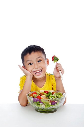 Child eating salad, shot in studio isolated on white background