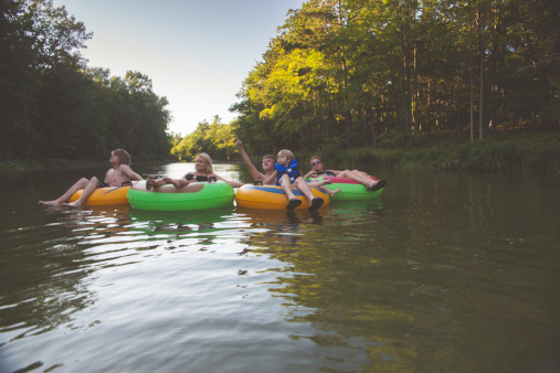 Family enjoying a day out on the river, relaxing in tubes and floating downstream. Shot in the Lower Platte river at the Sleeping Bear Dunes National Lakeshore in Michigan.