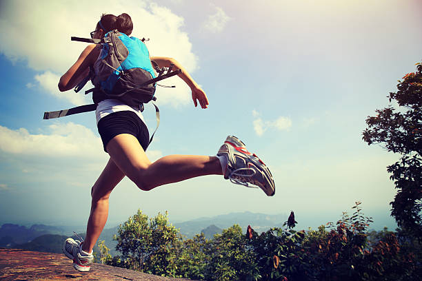 young asian woman hiker running on mountain peak cliff stock photo