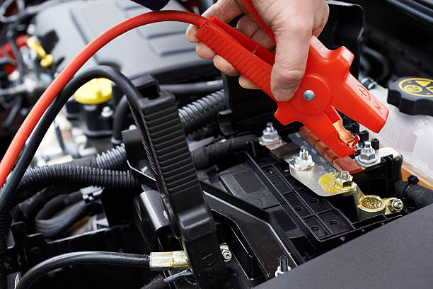 Close-Up Of Mechanic Attaching Jumper Cables To Car Battery stock photo