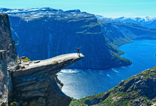 The summer view of Trolltunga (The Troll's tongue) in Odda ( Ringedalsvatnet lake, Norway) and man on rocks edge.