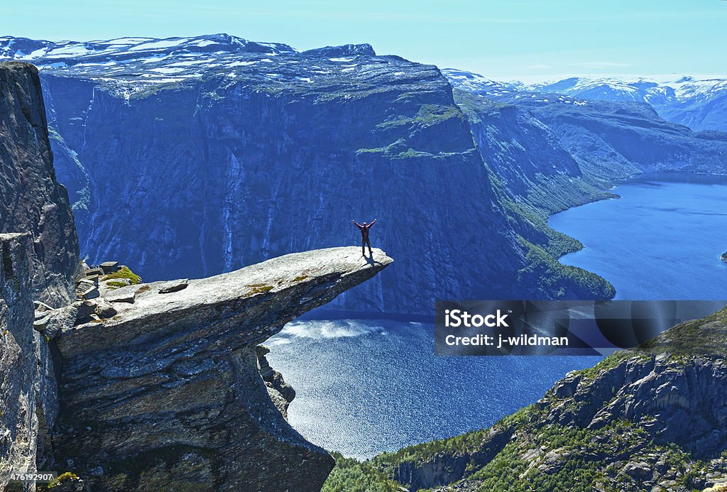 Trolltunga summer view (Norway) and man on rocks edge. The summer view of Trolltunga (The Troll's tongue) in Odda ( Ringedalsvatnet lake, Norway) and man on rocks edge. Trolltunga Stock Photo