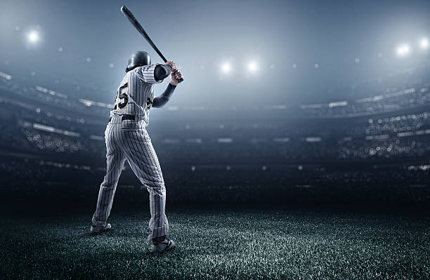 Baseball player in stadium A male baseballs batter makes a dramatic play.  The stadium is blurred behind him. Only the lights of the stadium shine brightly, creating a halo effect around the bulbs. baseball sport stock pictures, royalty-free photos & images