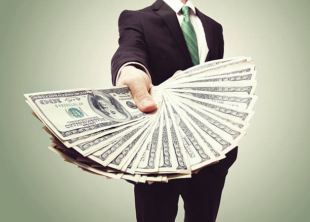 Business Man Displaying a Spread of Cash Business Man Displaying a Spread of Cash over a green vintage background giving money stock pictures, royalty-free photos & images