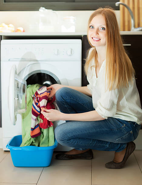 istock blonde woman putting clothes in to  machine 476197959