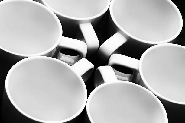 Six white cups in a circle. Black and white photo.