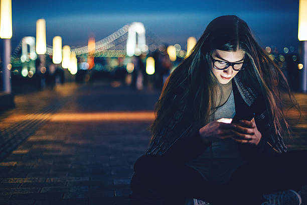 istock Smiling young woman with smart phone at night 476202706