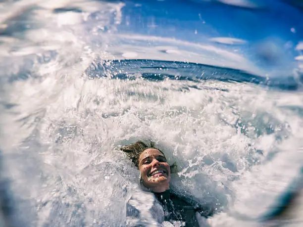 A woman takes a selfie while playing in clean waves. 