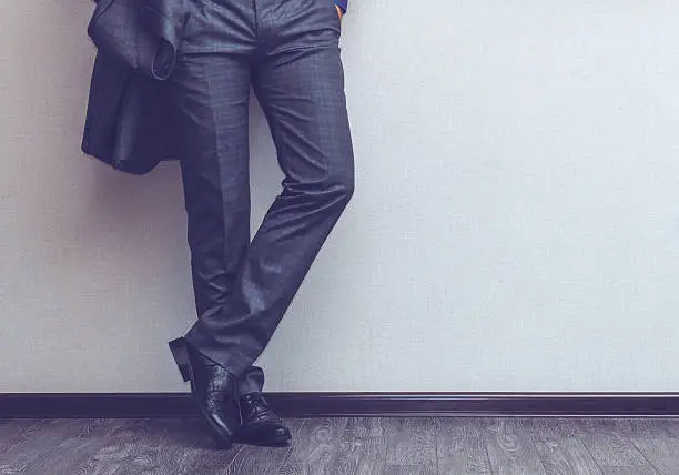 Young fashion businessman's legs in classic suit and shoes on wooden floor