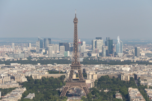 Aerial view over Paris cityscape with main landmark The Eiffel Tower and La Défense district in background.