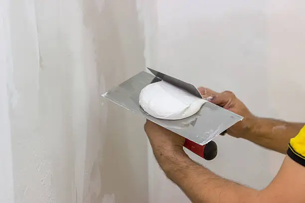 Mixing skimming plaster on trowel for the patching