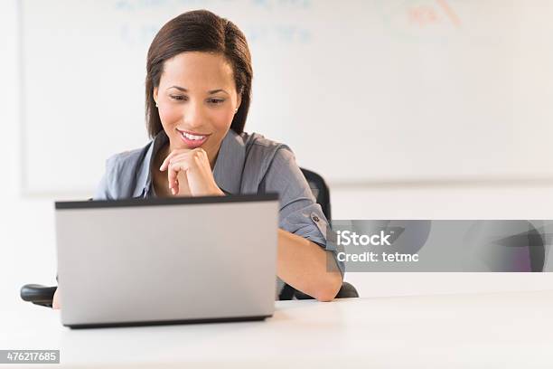 Businesswoman With Hand On Chin Using Laptop At Desk Stock Photo - Download Image Now