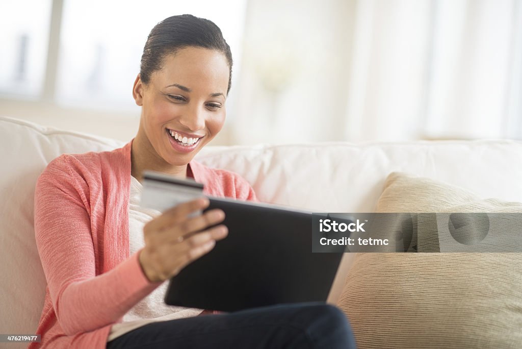 Woman With Credit Card And Laptop Shopping Online At Home Happy young woman with credit card and laptop shopping online at home African-American Ethnicity Stock Photo