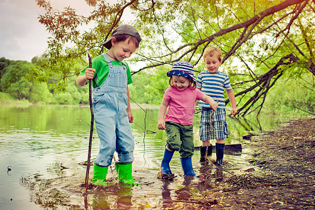 Little boys and girl playing near a lake in summer