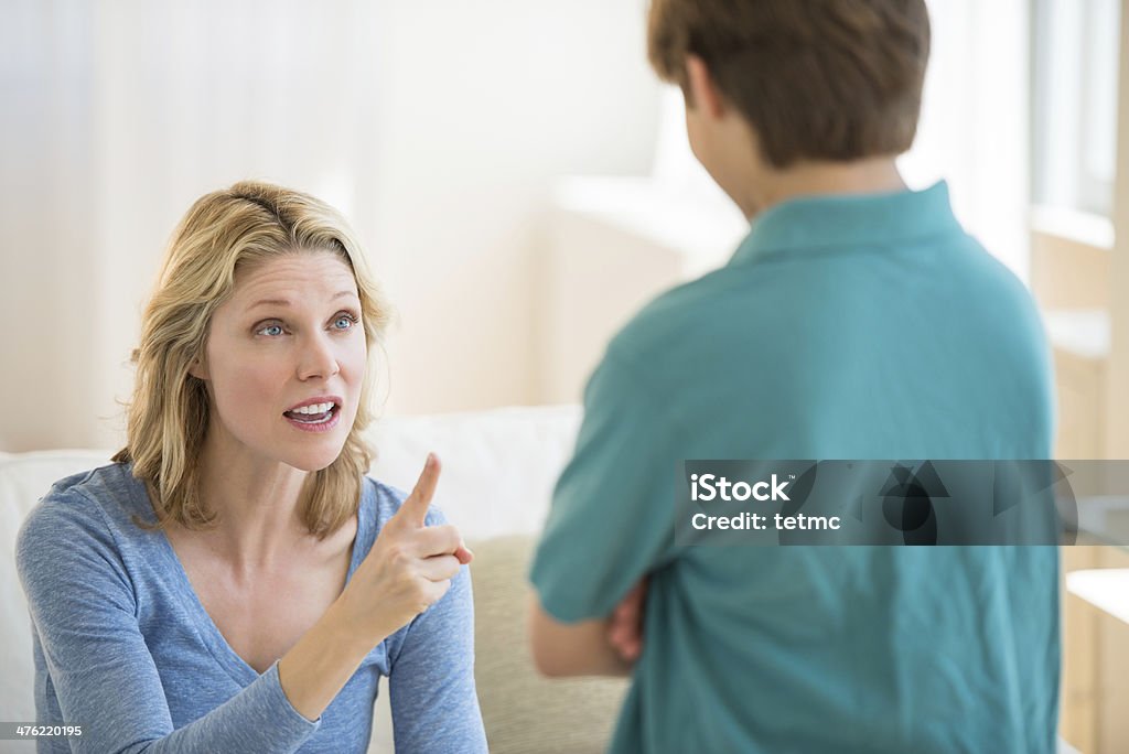 Angry Mother Scolding Son At Home Angry mother gesturing while scolding son at home Mother Stock Photo