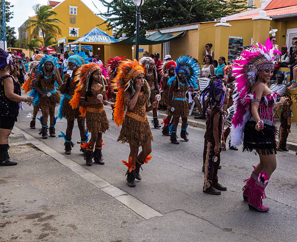 Os participantes vestida com trajes nativos de março e dança no desfile de carnaval - foto de acervo
